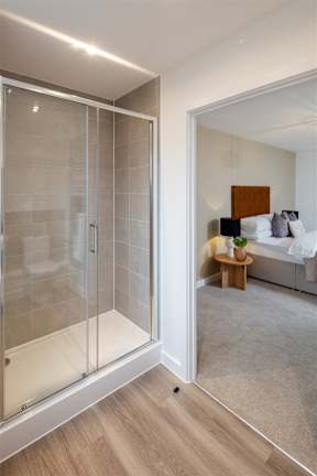 A modern bedroom with a glass door and a bed with white bedding.