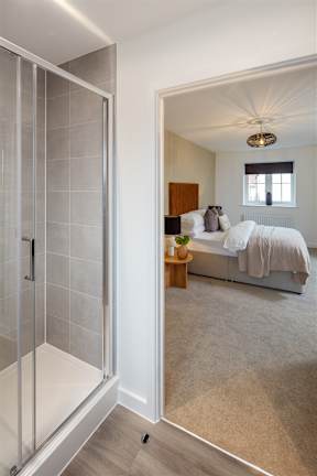A modern bathroom with a walk-in shower and a bedroom with a bed and a window.