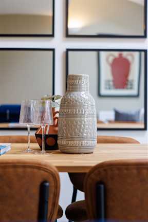 A table with a vase and glasses on it.