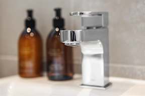 A bathroom sink with a soap dish and two bottles of soap.