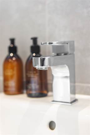 A bathroom sink with a faucet and three bottles of soap.