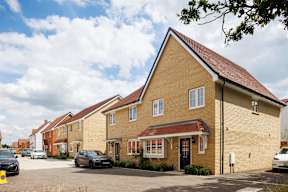 A row of houses with cars parked in front.