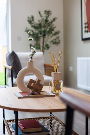 A table with a vase, a book, and a small plant on it.