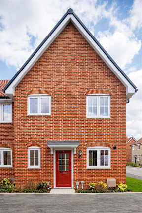 A red brick house with a white door and windows.