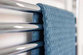 A close up of a blue towel hanging on a white radiator.