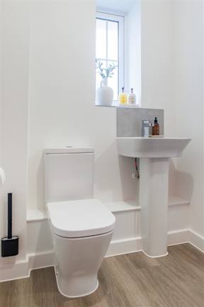A white toilet with a white sink and a white shelf above it.