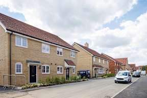 A row of houses with cars parked in front.
