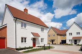 A white house with a red roof is in front of a row of similar houses.