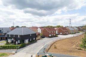 A residential street with houses on both sides and a road sign in the foreground.