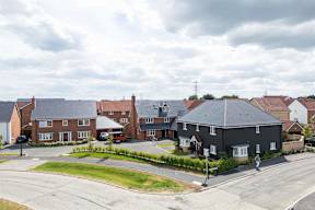 A residential area with houses and a person walking on the road.