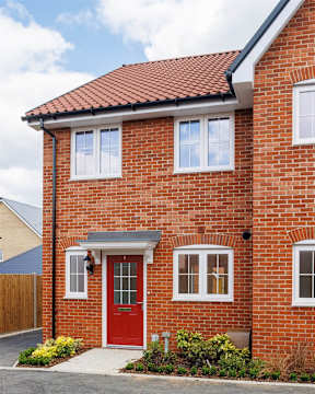A red brick house with a white door and windows.