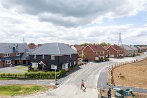 A residential area with houses and a pedestrian walking on the sidewalk.