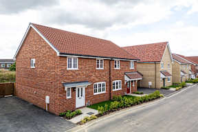 A row of houses with a red brick house in the front.