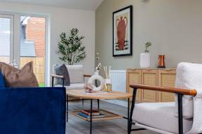 A living room with a blue couch, a white chair, and a framed picture on the wall.