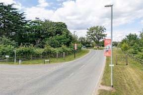 A road with a sign on the right side and trees on both sides.
