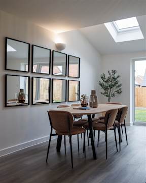 A dining room with a table and chairs and a wall of mirrors.