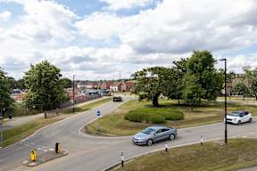 A car is driving on a road with a blue circular sign on the left.