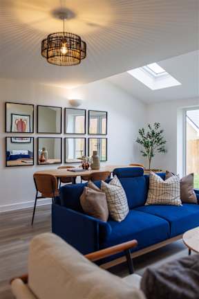 A blue couch with pillows and a wooden table in front of a wall with framed pictures.