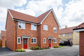 A red brick house with a black car parked in front.