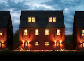Three houses with lit windows and doors are shown at dusk.