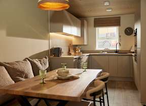 A modern kitchen with a wooden table set for two.