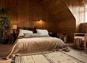 A bedroom with a large bed and wooden walls.