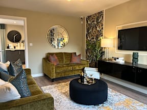 A living room with a green couch and a round mirror on the wall.