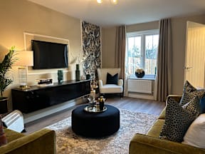A living room with a black ottoman and a green couch.