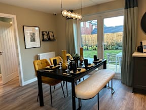 A dining room with a table set for two and a view of a backyard.