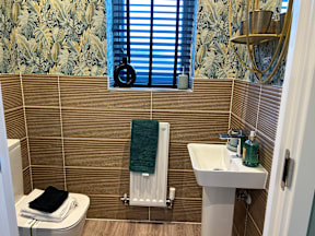 A bathroom with a toilet, sink, and a window with blinds.