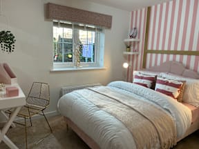 A bedroom with a bed, chair, and a window with a view of a garden.