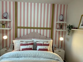 A bedroom with a bed, two nightstands, and striped wallpaper.
