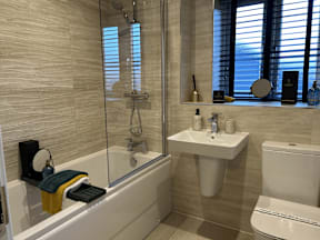 A bathroom with a white toilet, a white sink, a white bathtub, and a glass shower door.