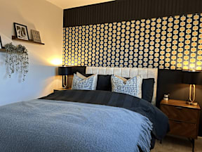 A bedroom with a bed, nightstand, and wall decor.