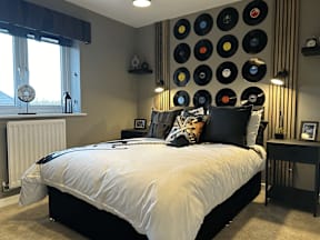 A bedroom with a bed, nightstands, and a wall of vinyl records.