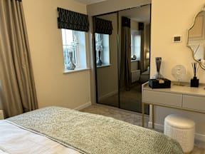 A bedroom with a large bed and a vanity table with a mirror.
