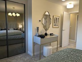 A bedroom with a bed, vanity, and mirror.