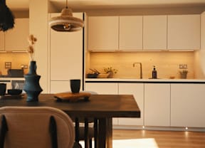 A kitchen with a table and chairs in the foreground and a counter in the background.
