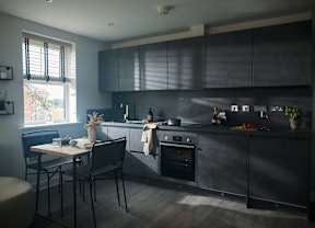 A modern kitchen with dark grey cabinets and a black oven.