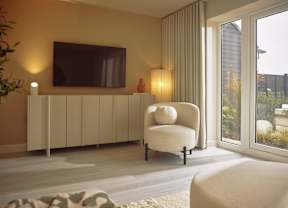 A living room with a white chair and a television mounted on the wall.