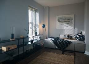 A modern bedroom with a bed, a glass shelf, and a rug.
