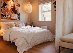 A bedroom with a large bed and a colorful painting on the wall.