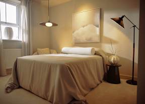 A bedroom with a bed, a lamp, and a painting on the wall.