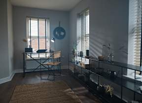 A room with a desk, chair, and shelves with various items.