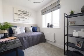a bedroom with a bed and a desk and a window