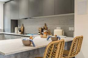 A kitchen with a marble countertop and wicker chairs.