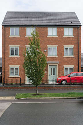 A red car is parked in front of a brick building.