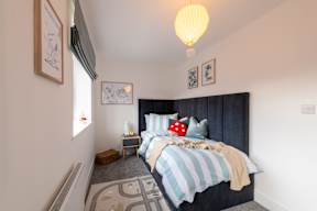 A bedroom with a bed, nightstand, and window.