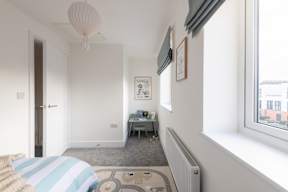A room with a bed, a desk, and a window.