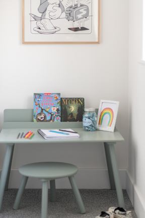 A desk with a green chair and a rainbow-colored object on it.